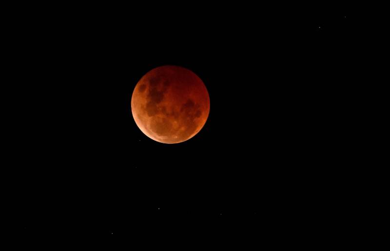 An image of the moon with a reddish tint.