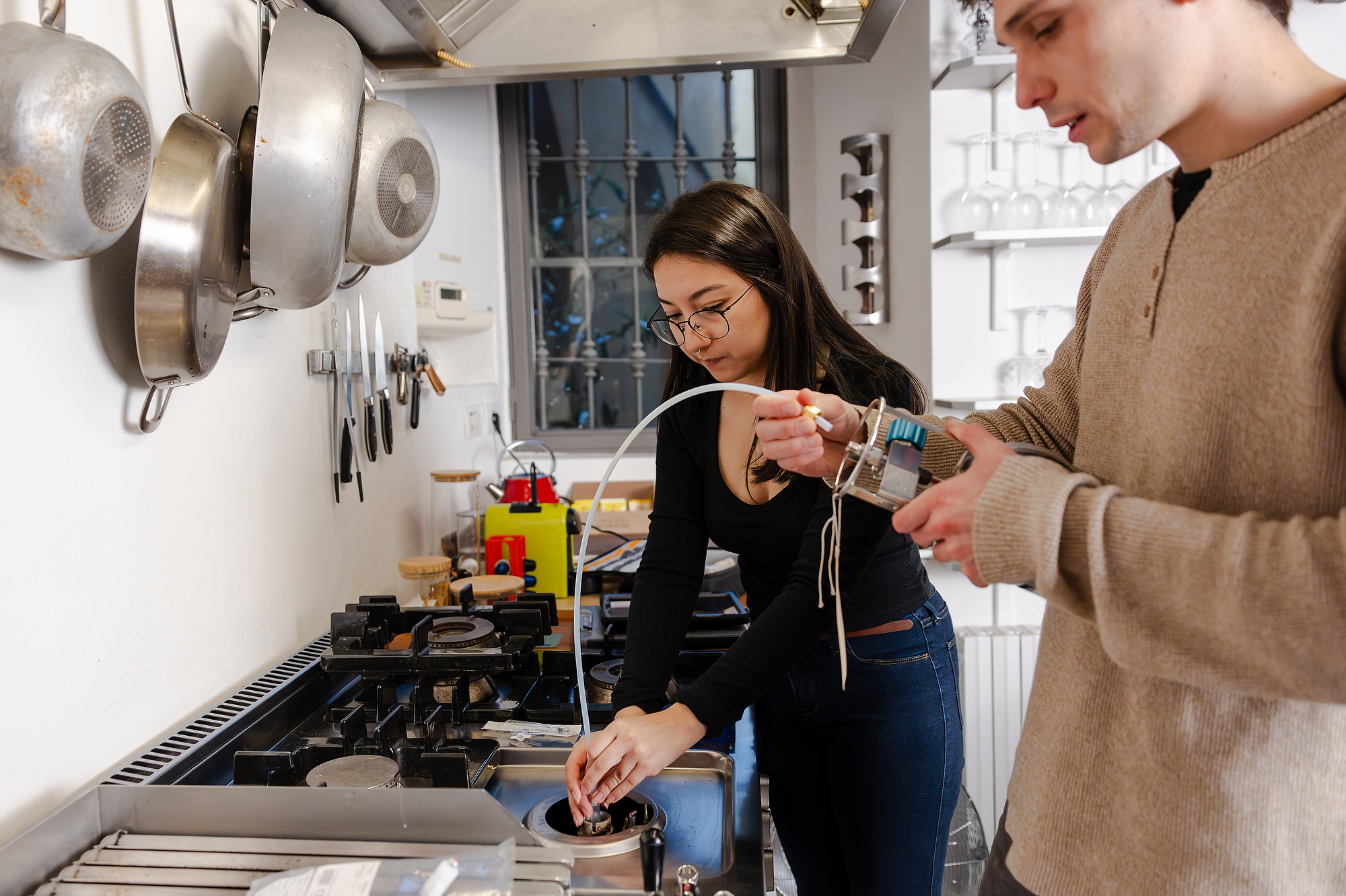 A person holds a machine near a gas stove.