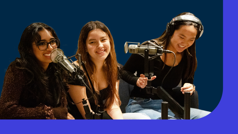 Three students sit around microphones in a recording studio