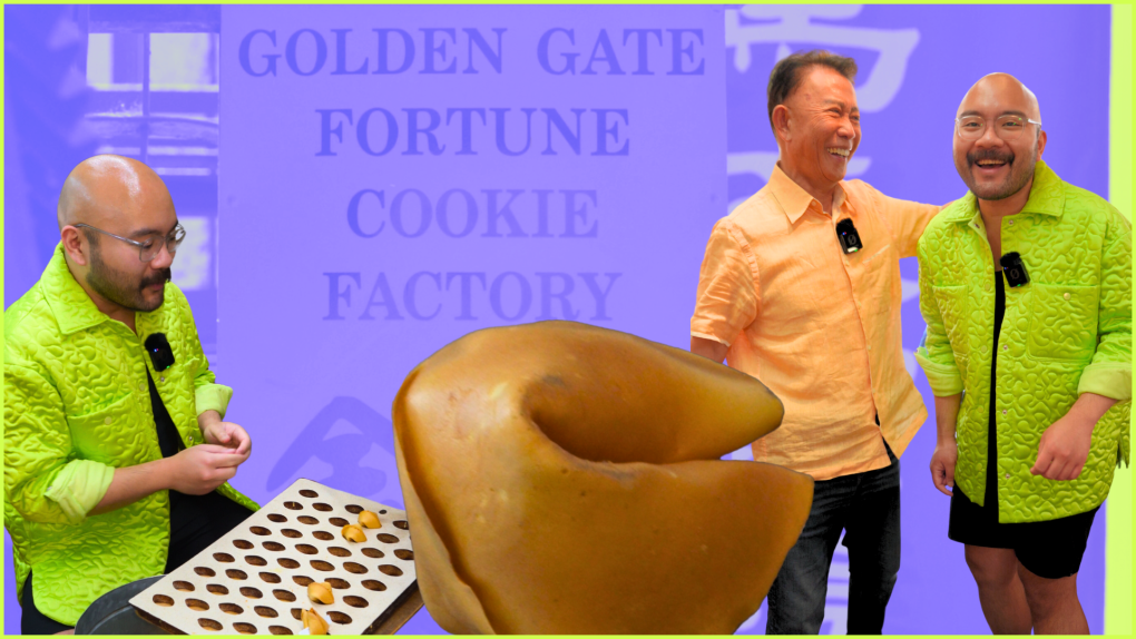 Martin Yan, an older Chinese man wearing a salmon shirt stands next to Josh Decolongon, a young Filipino man with a bald head, glasses and a neon green coat. There is a large fortune cookie in the foreground.