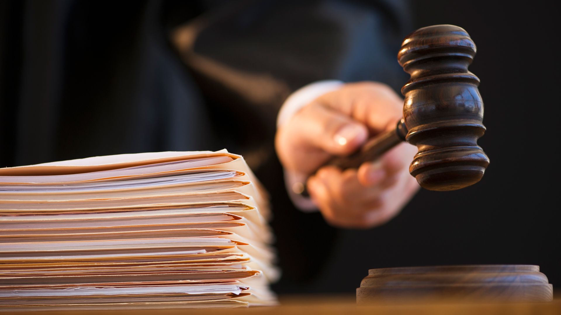 Judge holding gavel next to stack of papers