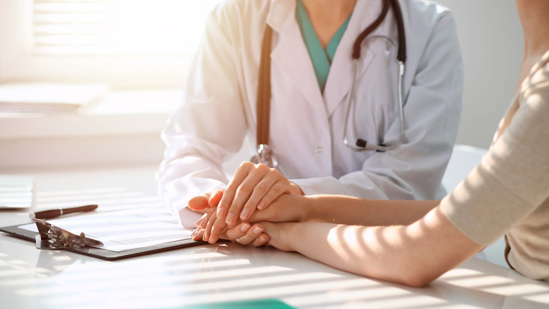 A doctor reassures a patient while sitting at a desk in a clinic.