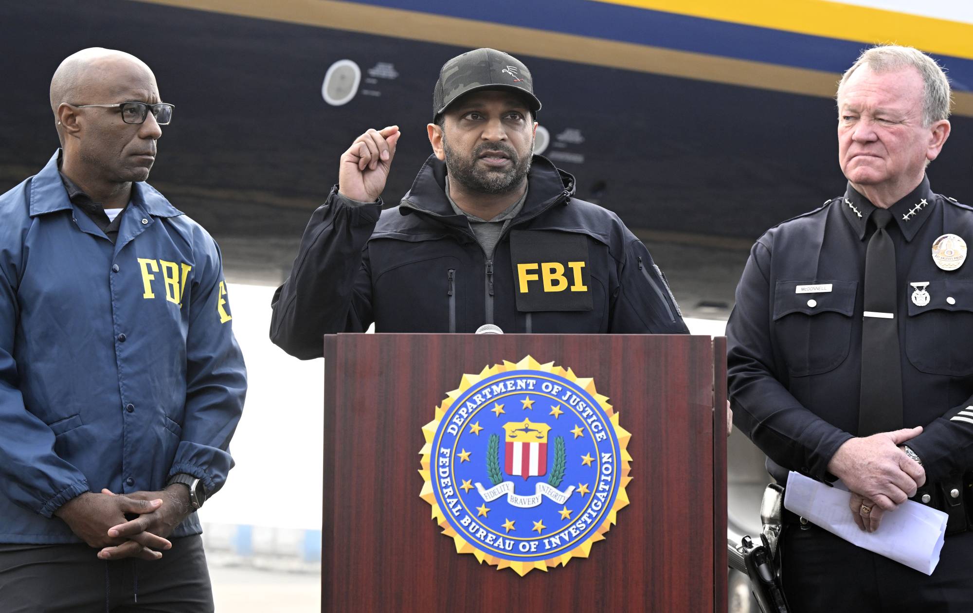 FBI Director Kash Patel, center, speaks during a press conference on the tarmac at Ontario International Airport on Friday, Jan. 23, 2026 as the FBI's Akil Davis, left, and Los Angeles Chief of Police Jim McDonnell, right, look on.