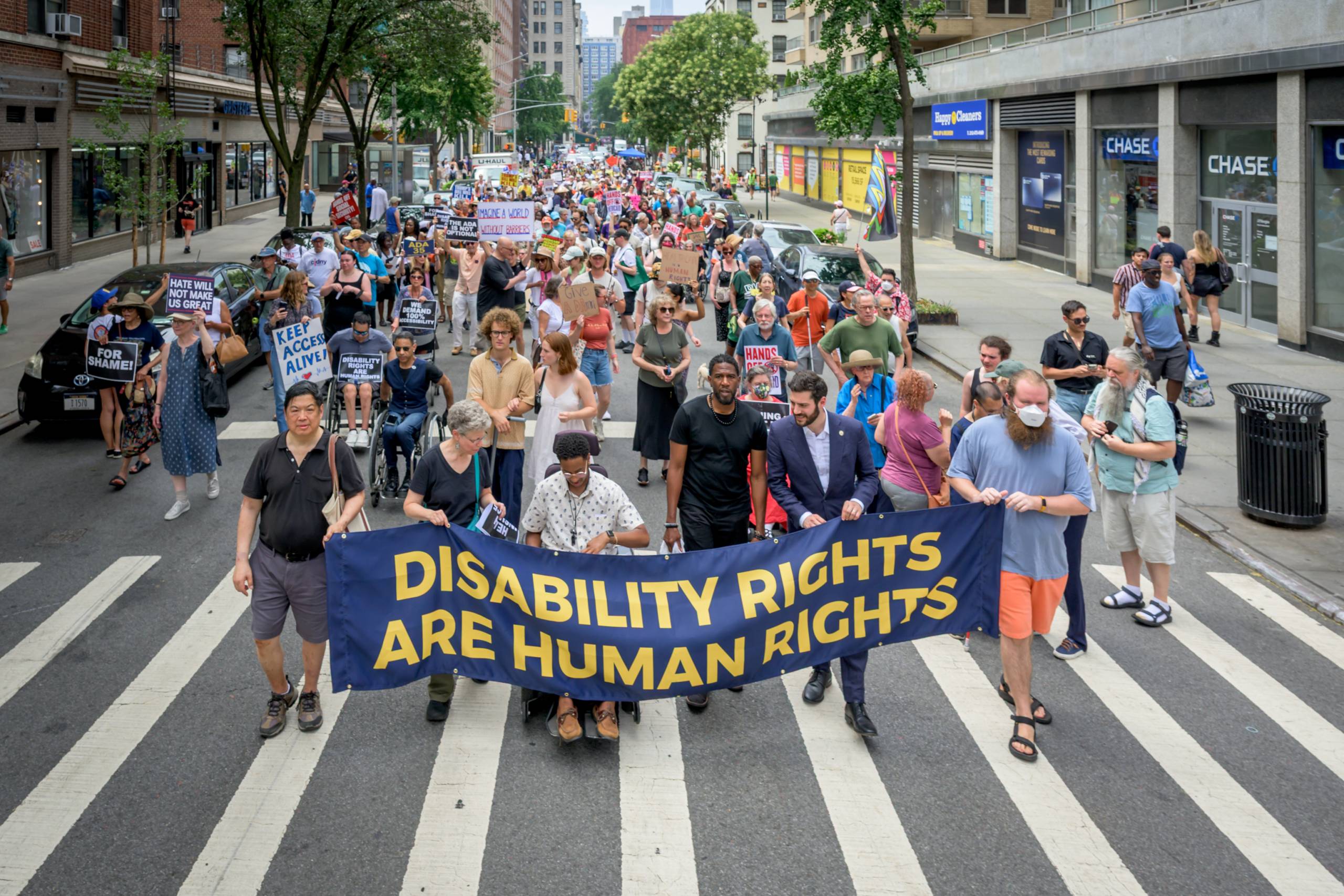Participants hold a banner at a protest labeled, "Disability Rights are Human Rights"