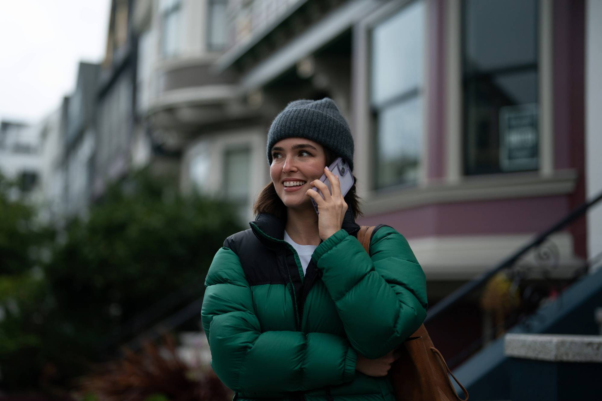 Zoey Deutch on her phone in front of San Francisco homes