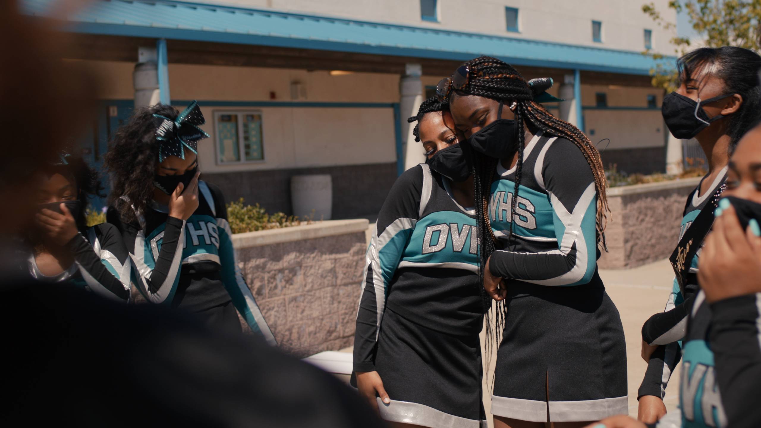 Students in cheer uniforms and face masks gather outside Deer Valley High School in Antioch, CA