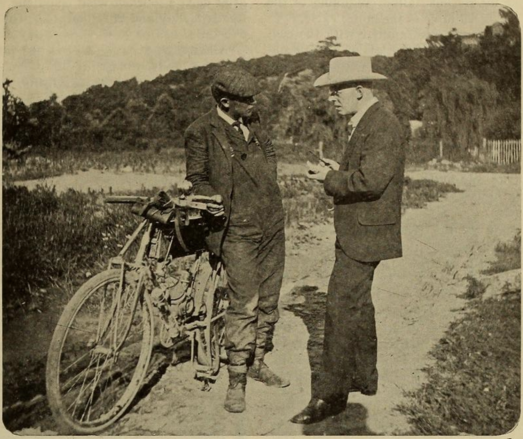 An old magazine photograph of two men and a bicycle. 